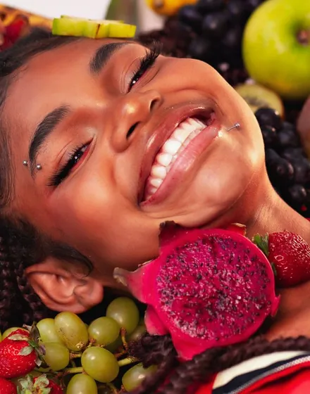 Mulher sorrindo cercada de frutas