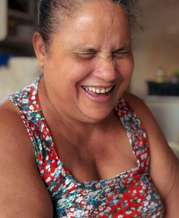 Mulher sorrindo, de olhos fechados
