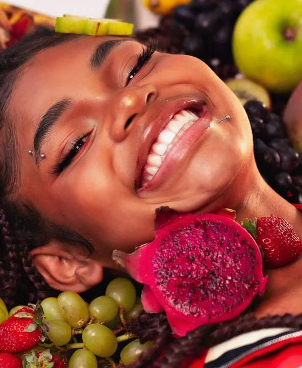 Mulher sorrindo cercada de frutas